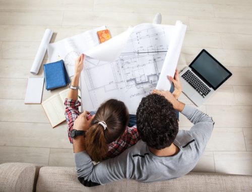 Un couple étudiant les plans papiers pour un futur logement